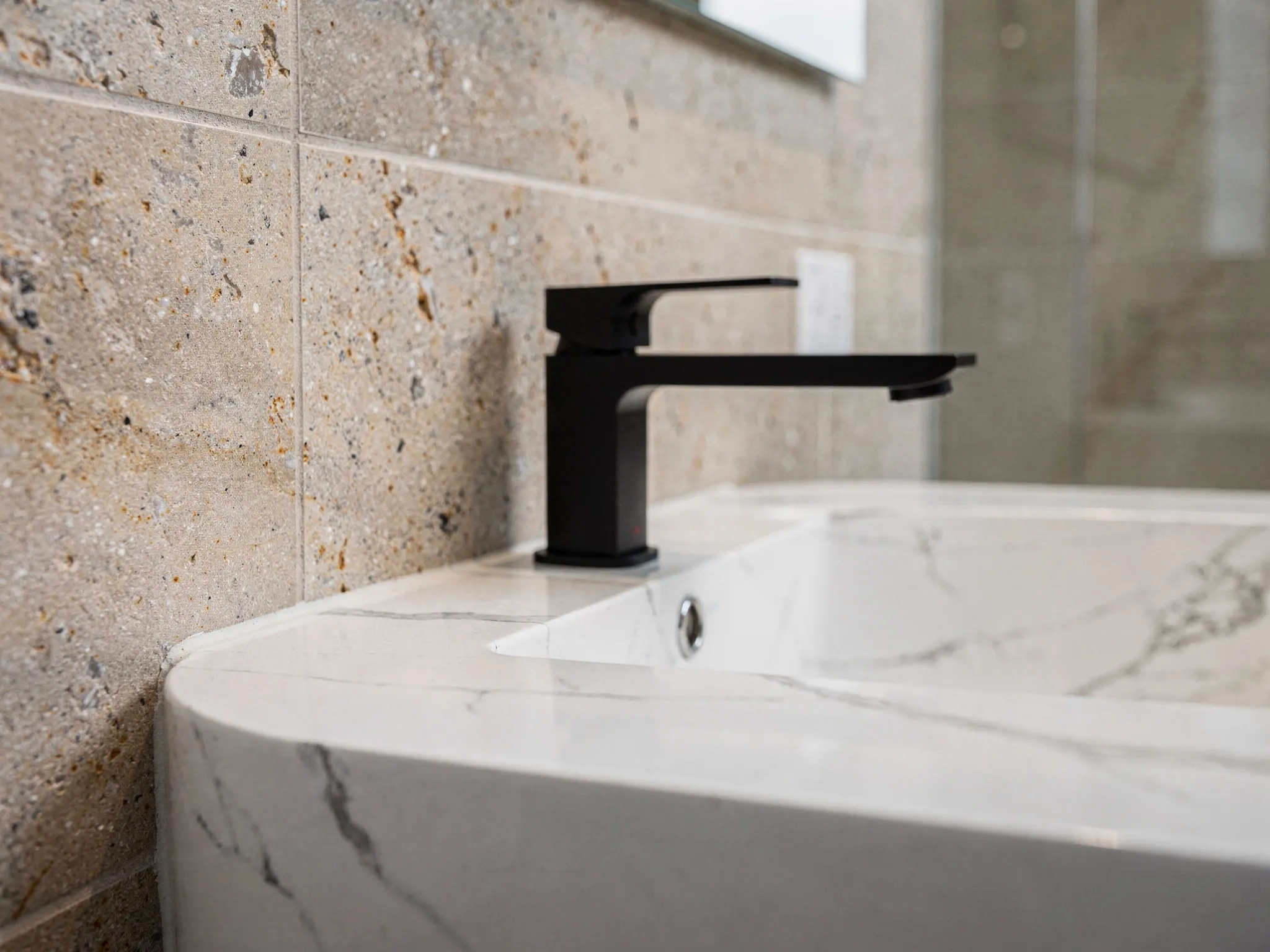White quartz vanity top paired with a matte black wall-mounted faucet — clean lines, zero caulk smears.