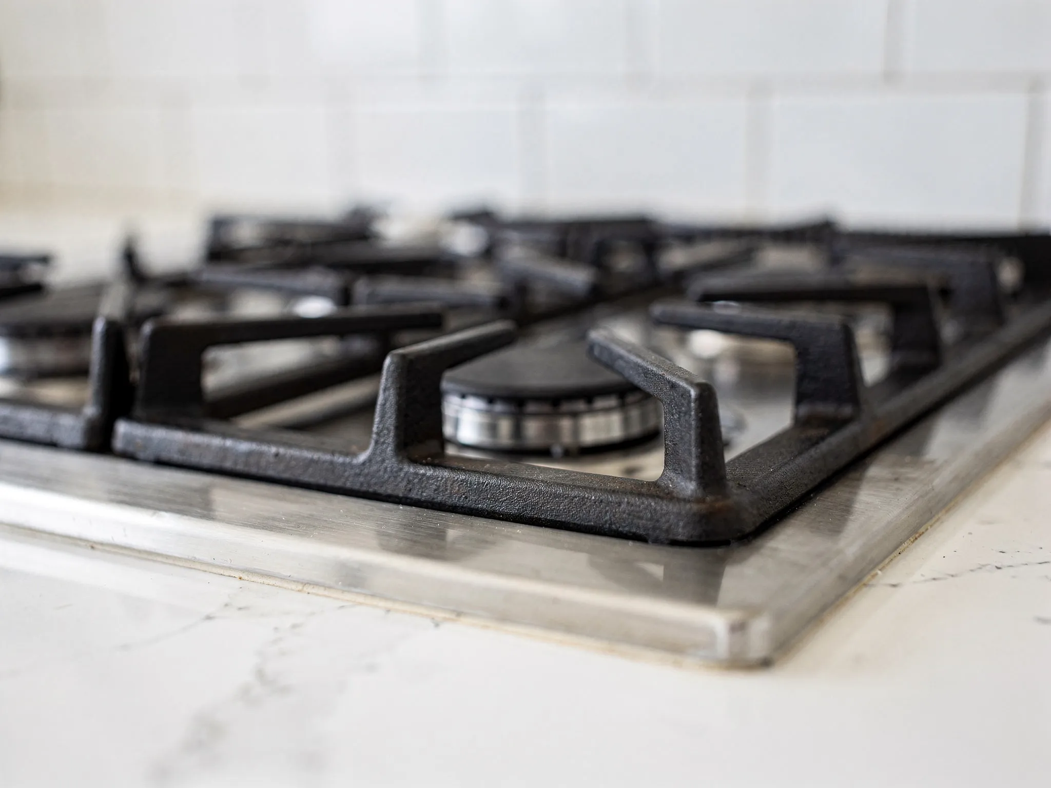 A professional-grade gas range framed by pure white subway tile, grout lines laser-straight.