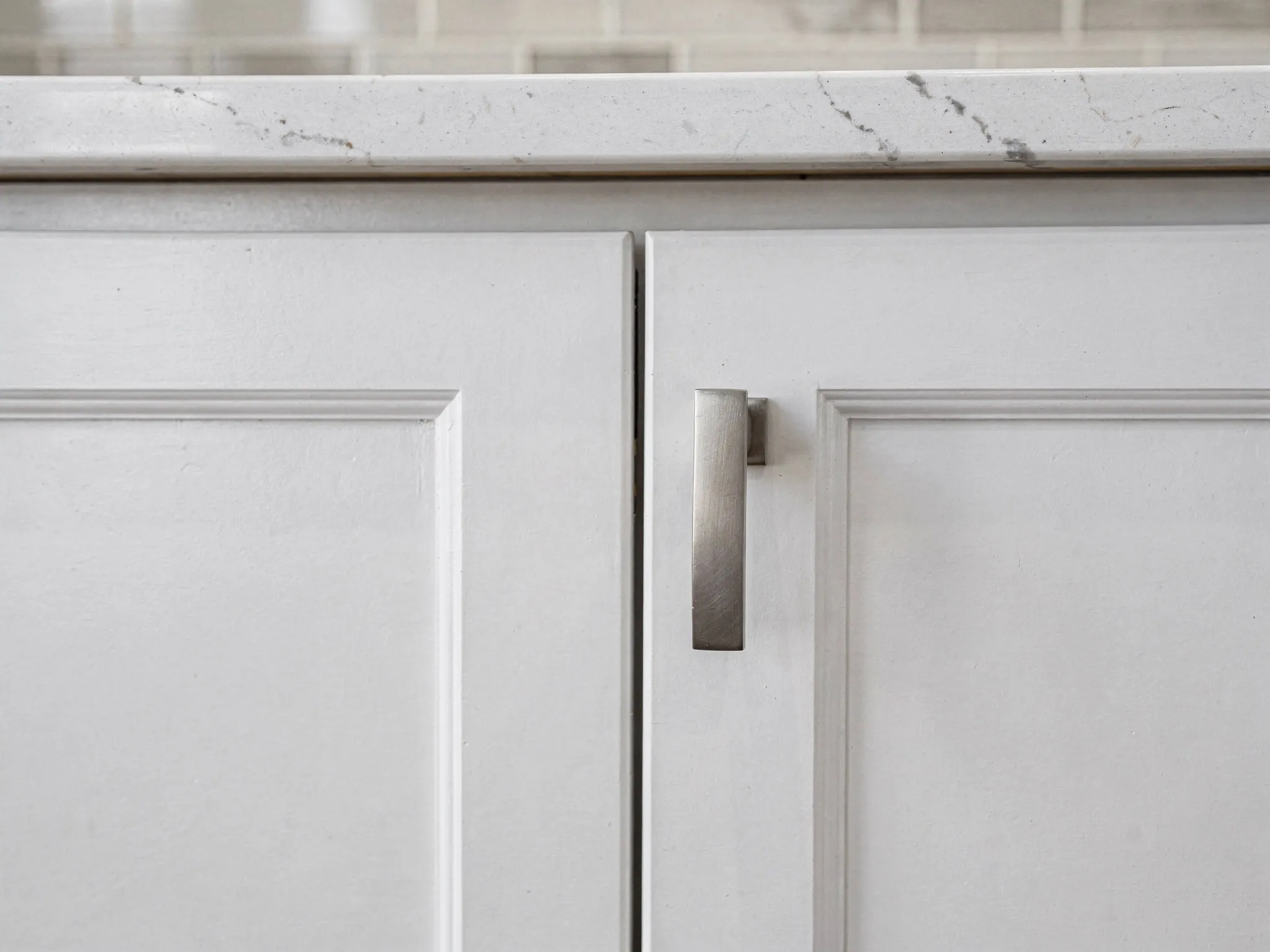 Crisp white shaker cabinet doors with brushed nickel pulls, aligned to the millimeter.